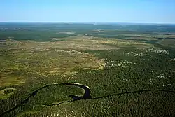 Paysage de toundra presque plar à perte de vue avec une méandre d'une rivière vue depuis un drone.