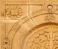 Gros plan sur le décor floral et sur d'autres ornements d'un panneau sculpté de la façade du portique occidental.