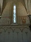 Travée centrale du mur nord avec de bas en haut: les arcades entrecroisées, une frise ornementale, une fresque partiellement reconstituée et un faux appareil en rouge brique.
