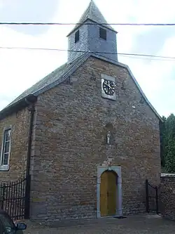 Édifice religieux en pierre de style roman avec un clocher et une horloge.