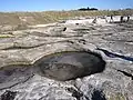Trous circulaires sur l'estran rocheux granitique à l'ouest de Guilvinec, qui correspondent à la découpe et l'extraction de socles pour la construction de calvaires ou de croix.