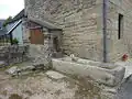 Puits, auge et pompe accolés à une maison à Kermaria.