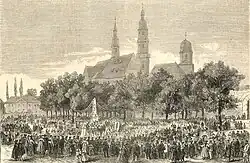 Gravure ancienne montrant une foule entourant un monument au mort situé devant une église baroque.