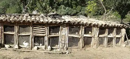Série de clapiers extérieurs à 2 étages en briques et bois, portes en grillage à poules fermées par un loquet de métal et coincées en bas par une grosse pierre, couverture de tuiles romaines.