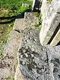Cupules sur une dalle de schiste à l'entrée de l'enclos paroissial, traces probables d'un culte préchrétien