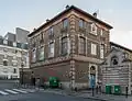 Bâtiment en pierre meulière et brique du 106, rue Brancion, à l'angle sud-est du site. Il est décoré, entre autres sculptures, d'une tête de cheval et porte l'enseigne du théâtre Le Monfort.