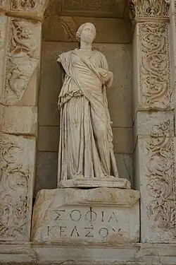 Image d'une statue de femme avec une inscription en grec sur son pilier.