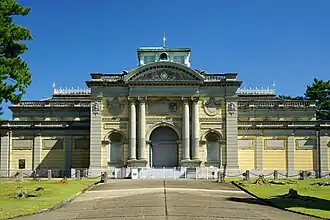 Photo de l'entrée d'un bâtiment : une porte monumentale est entourée de colonnes rondes.