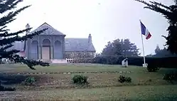 Un perron de cinq marches relie la véranda de treillage (sans vitres désormais) au gazon pelé et à la pièce principale de l'aile centrale