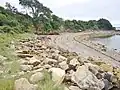 Grève à la pointe du Roz bordée de blocs, résidus de carrière en pierre de Logonna provenant de la carrière du Roz toute proche.