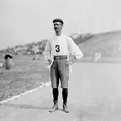 Un homme avec un béret, un pantalon coupé et un maillot avec le numéro 3.