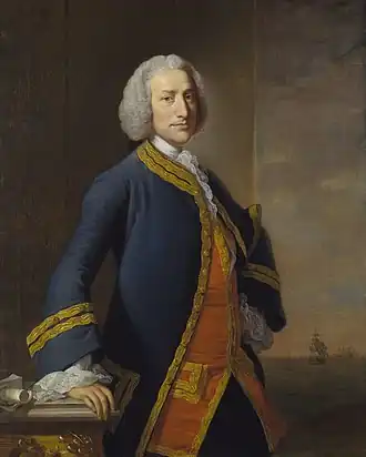 Portrait en pied, 50 ans environ, uniforme bleu sur veste rouge, parements dorés, main droite appuyée sur coin de bureau, jabot de dentelle, à droite fond marin sombre avec un voilier