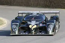 Photographie d'une voiture de sport-prototype verte et grise, vue de face, sur une piste.