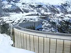 Un barrage au milieu de montagnes enneigées.