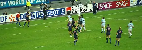 Plan large de joueurs de rugby en action sur un terrain.