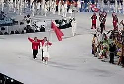 2 personnes en rouge défilant derrière une autre vêtue de blanc et portant un panneau où il est inscrit Maroc