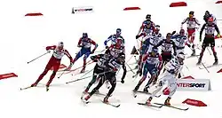 Plusieurs fondeurs de face, prenant u virage en descente sur leur gauche.