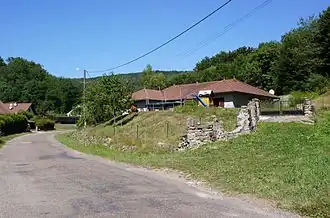 Une petite maison au pied d'une colline boisée.