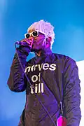 Homme qui chante, tenant le micro sans fil entre ses mains. Image en couleur.