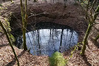 Un grand trou en entonnoir remplit d'eau.
