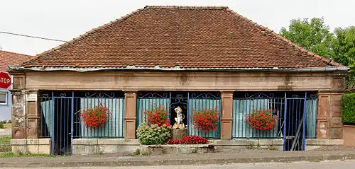 Petit bâtiment en grès rose avec toit à quatre pans.