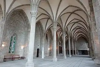 Ensemble de la salle des Hôtes : à gauche, les accès et la troisième cheminée ; au fond, la double cheminée.