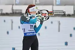 Biathlète, de face, en train de tirer sur sa gauche.