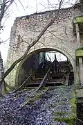 Une rampe métallique passant dans la voute d'un grand bâtiment de pierre et de brique.