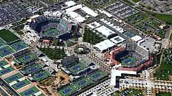 Vue aérienne des courts de tennis de l'Indian Wells Tennis Garden. On distingue bien les deux courts principaux, entourés de hautes tribunes et reliés par une allée centrale bordée de palmiers