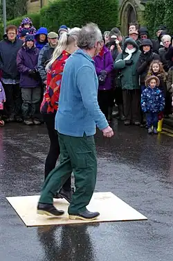 Deux personnes, un homme et une femme, dansent devant une foule, sous la pluie.