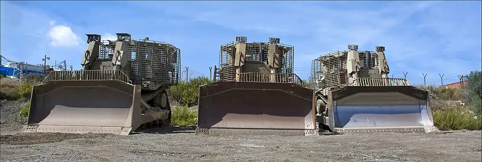 Trois Caterpillar D9 de Tsahal équipés d'un blindage à lamelles, stationnés près d'un avant-poste des forces armées israéliennes.