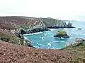 Îlot rocheux et falaises au débouché du vallon du ruisseau de Kergulan (limite communale entre Goulien et Beuzec-Cap-Sizun) ; à l'arrière-plan la Réserve naturelle du Cap-Sizun en Goulien.