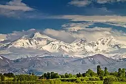 Des montagnes aux sommets dans les nuages mais avec des pentes enneigées avec une belle luminosité.