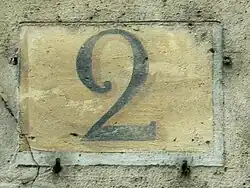 Numéro peint en noir sur fond ocre, conformément à la réglementation de 1805 pour les rues perpendiculaires à la Seine.