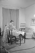 A Day in the Life of a Wartime Housewife- Everyday Life in London, England, 1941 (Un jour/Day dans la vie d'une femme au foyer en temps de guerre - vie de tous les jours à Londres, Angleterre, 1941). Madame Day met la table en prévision du dîner (...) : elle attend son mari, le lieutenant de la marine Kenneth Day (...).