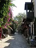 Une rue à Kaş avec des maisons traditionnelles et une tombe lycienne en arrière-plan