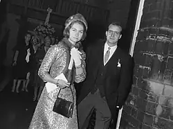 Photographie d'un couple, dont la femme porte un manteau brodé, une toque et une écharpe en fourrure et l'homme un costume trois pièces.