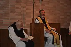 Photographie couleur de deux religieux assis dans un lieu de prière.