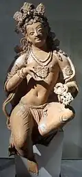 Deva (ou bodhisattva) assis dans la pose de délassement. VIIe – VIIIe&nbsp;siècle. Fondukistan (N-E Kaboul), Afghanistan. Terre séchée polychrome, H. 72, L. 24&nbsp;cm. Musée Guimet.
