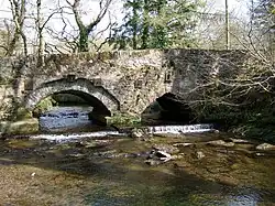 Un vieux pont à deux arches sur un petit cours d'eau.