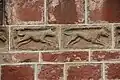 Détail du clocher, pierres sculptées (scène de chasse).