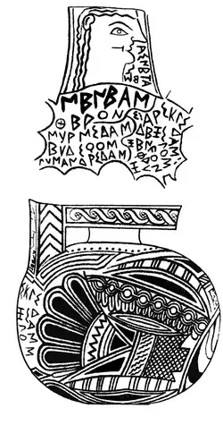 Objet décoratif ovale noir et blanc, avec une tête féminine stylisée en haut et des motifs complexes en bas, orné d'inscriptions grecques anciennes.