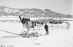 Un avion dont l'armature est visible posé sur la banquise, avec un homme à côté.