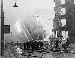 Des pompiers dirigent leurs lances vers des bâtiments en feu à Manchester après une attaque aérienne.