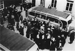 photographie en noir et blanc de patients d'un hôpital psychiatrique embarquant à bord de bus