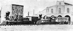 Photographie de deux trains tirés par des locomotives du XIXe siècle devant un bâtiment portant l'inscription « Ice House ».