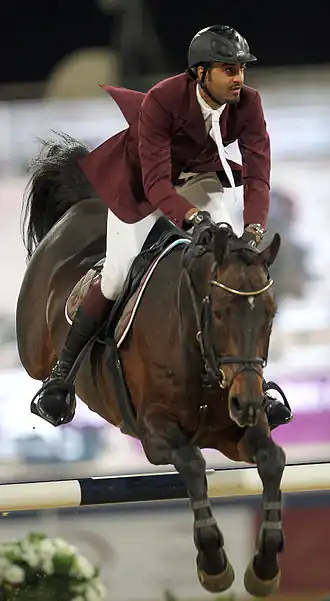 Photo de face d'un cheval et son cavalier franchissant un obstacle.