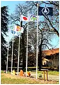 Drapeau comportant les armes de la région sur fond blanc, drapeau arboré (parmi cinq autres) à côté du drapeau du Japon au château Tsuji de Liergues en 2020