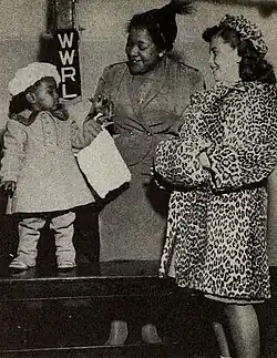Photographie d'une femme debout entre deux enfants vêtus de manteaux de fourrure.