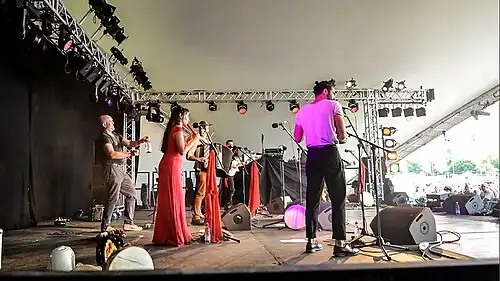 Mark Glanville&nbsp;(en) frappe avec une baguette une bouteille en verre au WOMAD avec le groupe Amaraterra.